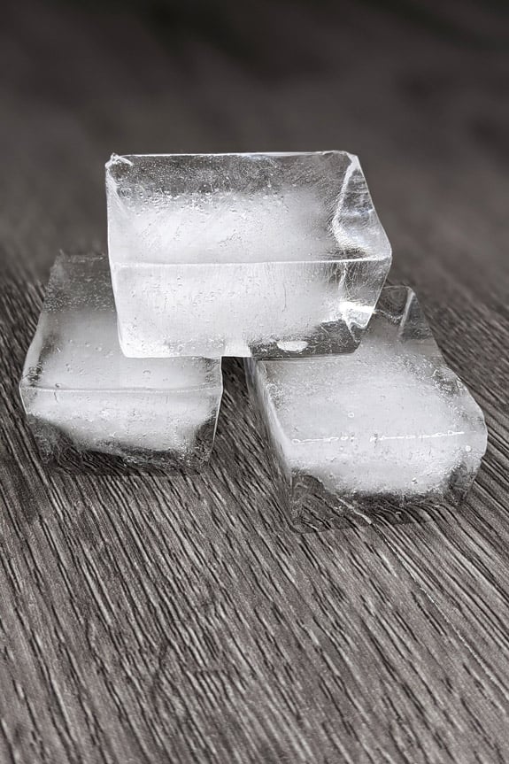 Three frozen ice cubes on a wooden floor