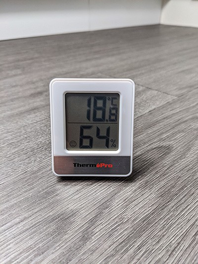 Small hygrometer with a built in thermometer on a wooden floor